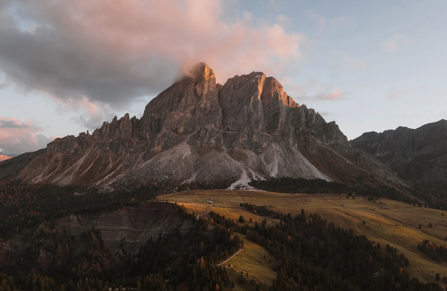 Gruppo delle Odle con enrosadira sopra prati alpini autunnali e larici dorati presso Funes nelle Dolomiti