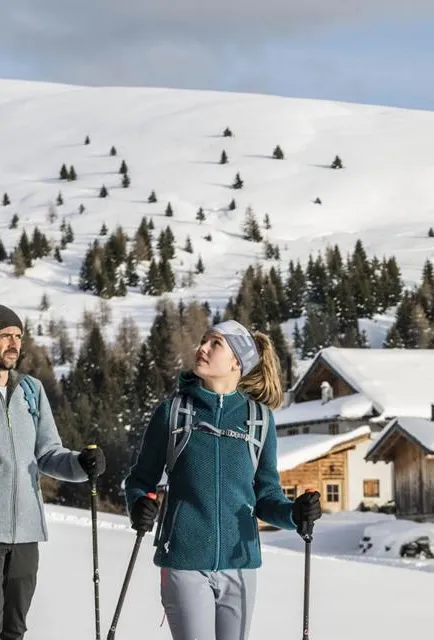 Winterlandschaft Lüsner Alm mit Blick auf verschneite Berggipfel und traditionelle Almhütten in Südtirol