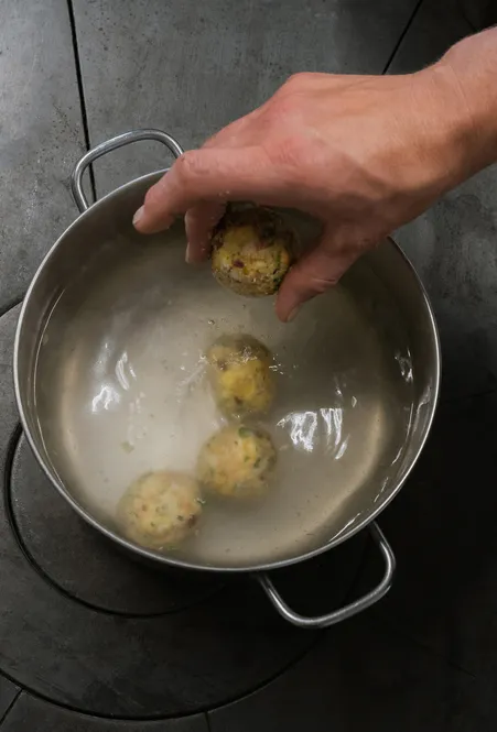 Canederli altoatesini fatti in casa con speck e erbe aromatiche vengono cotti tradizionalmente in pentola
