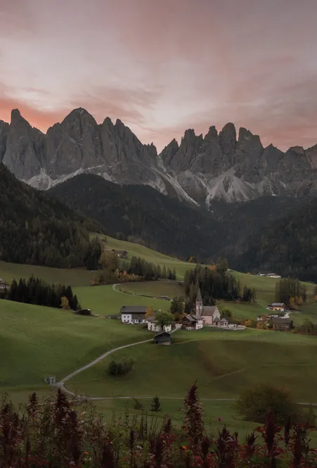 St. Magdalena in Villnöß bei Sonnenuntergang mit den Geisler-Spitzen der Dolomiten und herbstlichen Almwiesen