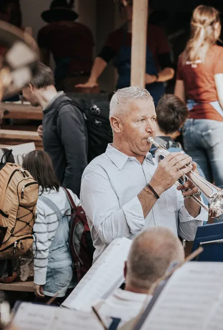 Blasmusikkapelle mit Trompetern spielt bei einem traditionellen Dorffest in Villnöß umgeben von Besuchern