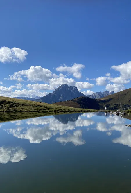 Mountain lake on Luson Alp with perfect reflection of Geisler Dolomites under brilliant blue sky in Villnöß South Tyrol