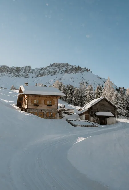 Verschneite Rodelbahn durch winterliche Wälder in Villnöß mit Blick auf die schneebedeckten Geislerspitzen