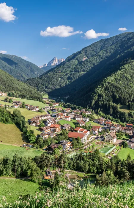 Frazione Paese a Luson in estate con chiesa parrocchiale