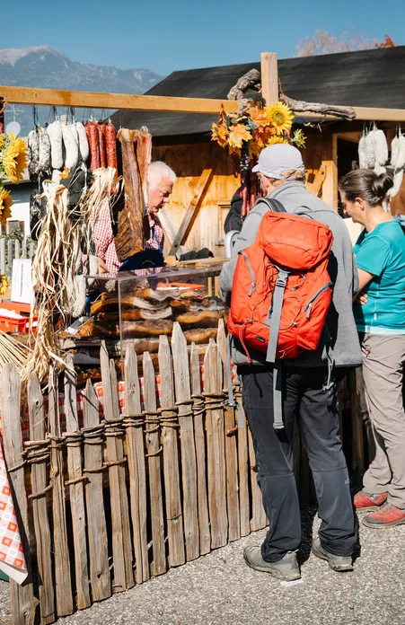 Market stall with hanging South Tyrolean sausages and speck at a farmers market in Villnöß hikers shopping