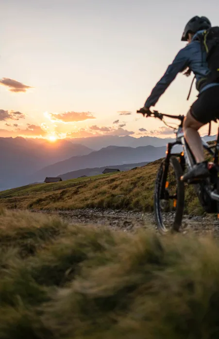 Ciclista sull'Alpe di Luson con vista panoramica sulle cime dolomitiche sullo sfondo