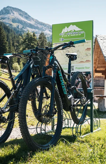 E-Bike Villnöß charging station with Specialized e-bikes in front of traditional alpine hut with Peitlerkofel view