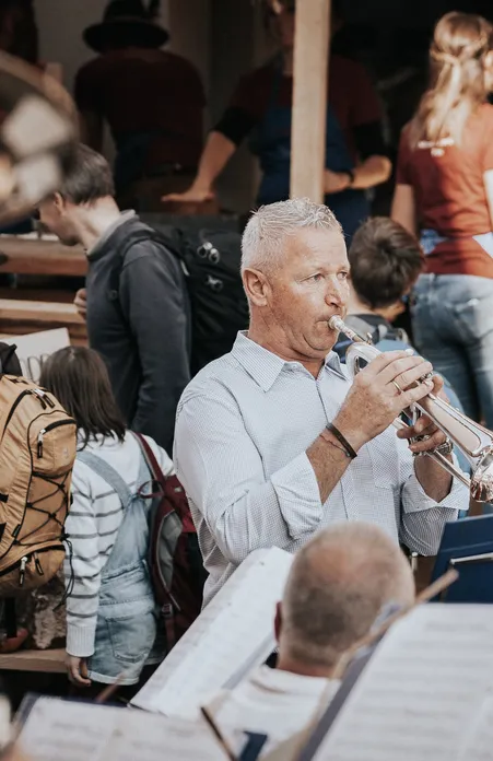 Brass band with trumpeters plays at a traditional village festival in Villnöß surrounded by visitors