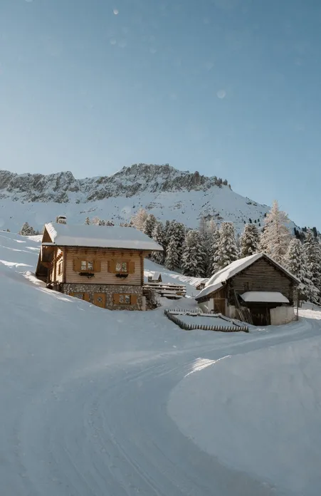Pista da slittino innevata attraverso boschi invernali a Funes con vista sulle Odle innevate