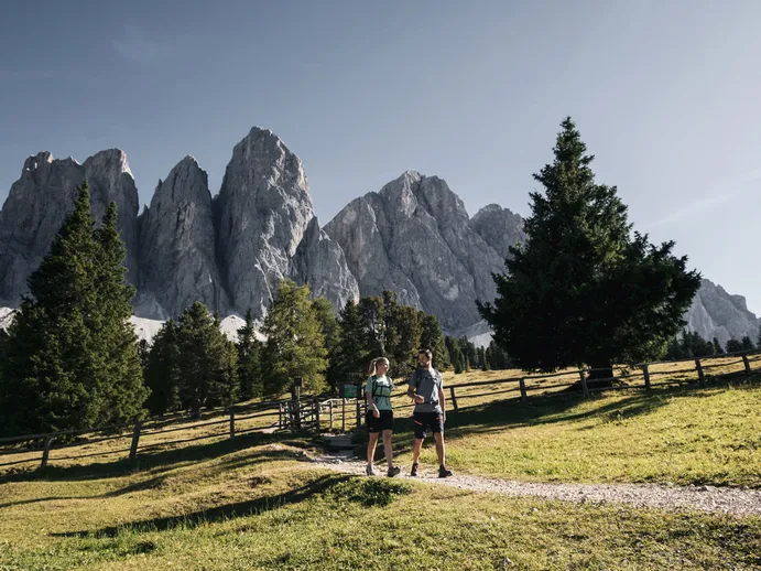 Due escursionisti su sentiero alpino sotto il gruppo delle Odle nel Parco Naturale Puez-Odle di Funes, Dolomiti altoatesine
